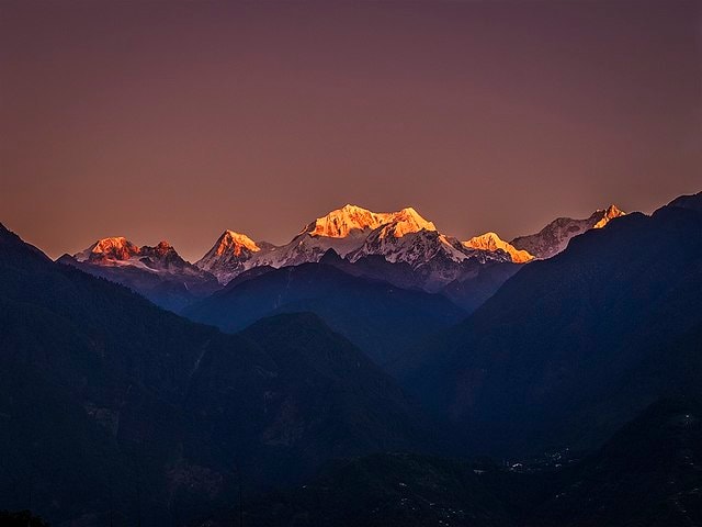 Kangchenjunga glowing at sunset above dark ridges