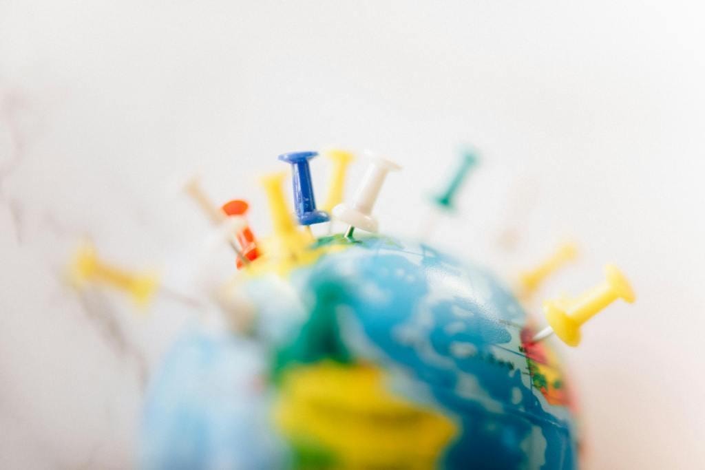 A small globe covered in colourful map pins