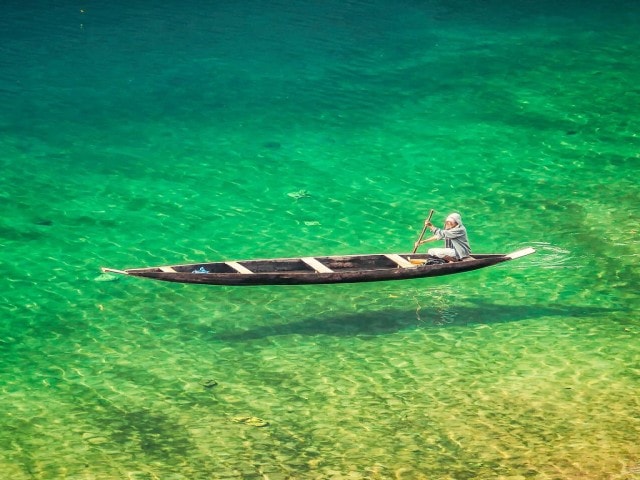 A wooden boat floating on the crystal clear water of the Dawki river